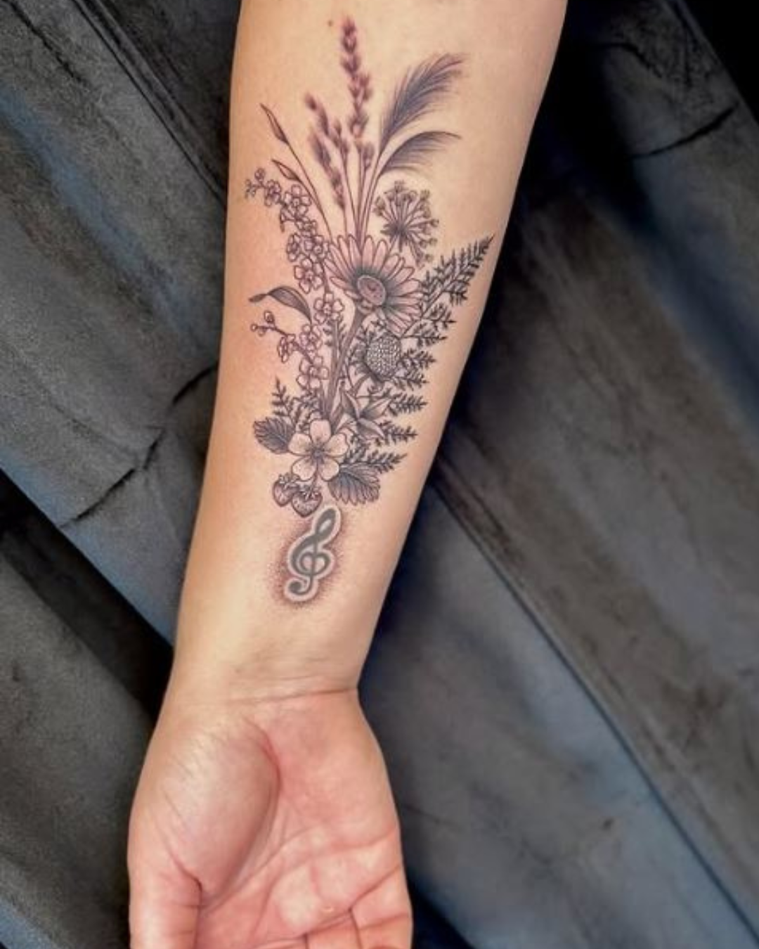 en kunds arm med en nygjord tatuering föreställande en blombukett 