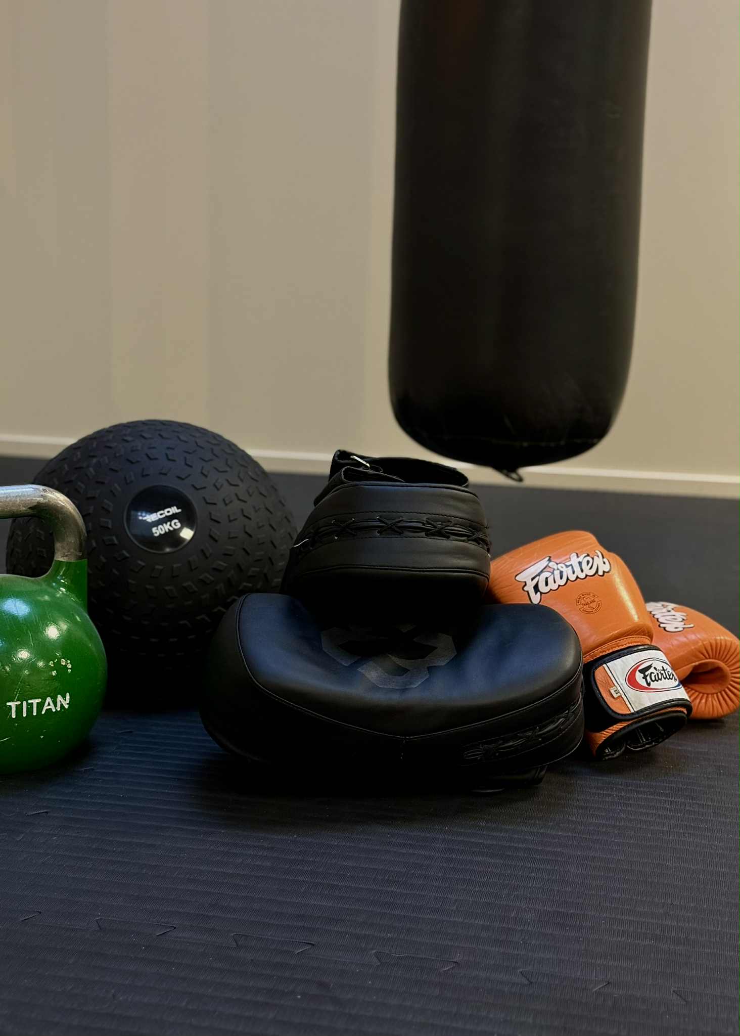 redskap till thai boxing står samlat på golvet intill en hängande boxningssäck